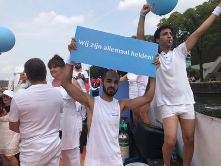 An Iranian on the board of the IranPride boat holds a sign says "We are all heroes"
